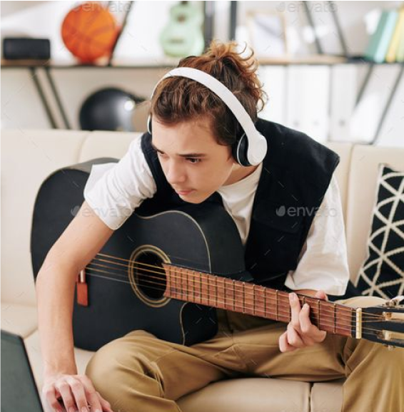 Photo d’une personne apprenant à jouer de la guitare, tenant une guitare acoustique ou électrique.