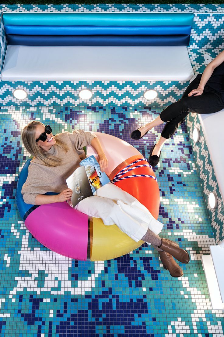 Photo d’une fille assise sur un ballon gonflable dans une piscine, en pose détendue.